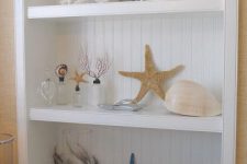 an open storage unit with corals, starfish, seashells and other sea stuff is a lovely decor idea for a living room or some other space