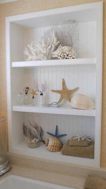 an open storage unit with corals, starfish, seashells and other sea stuff is a lovely decor idea for a living room or some other space