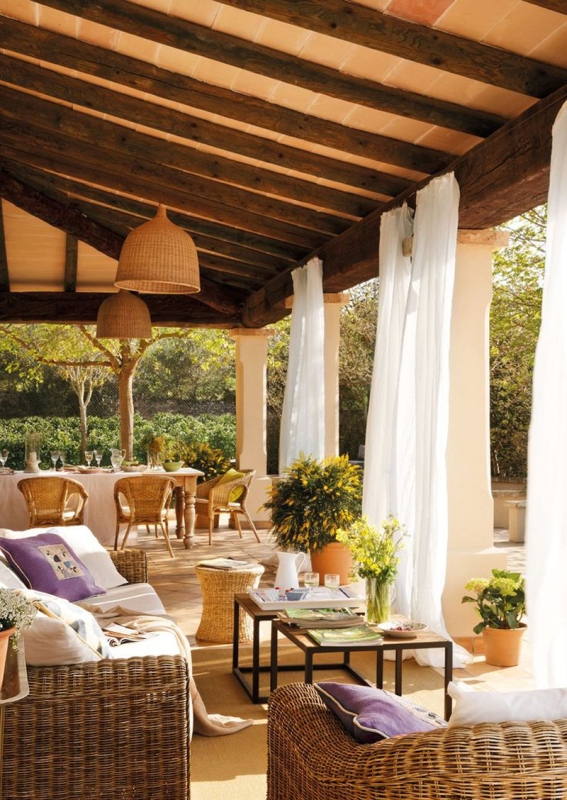 an outdoor-indoor space with a dining room, a vintage table and wicker chairs, wicker seating furniture, a duo of tables and yellow blooms