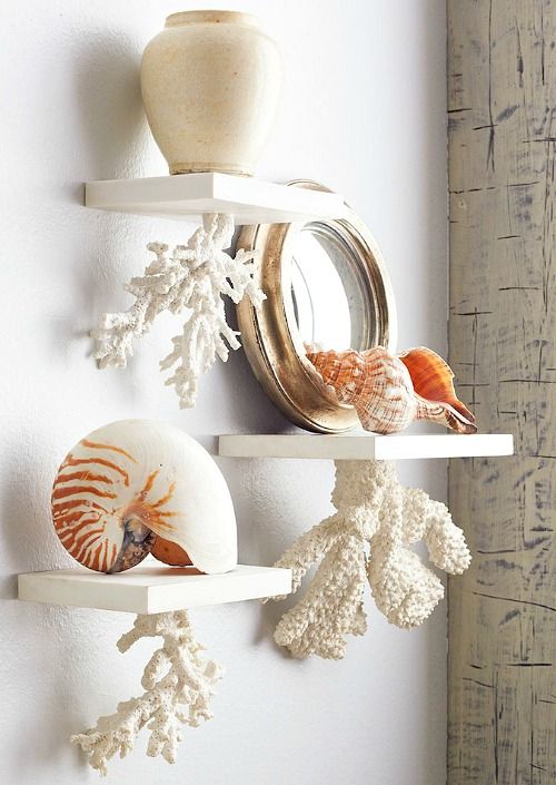 bathroom shelves with faux corals attached to them and with seashells and a mirror on them for giving a seaside feel to the space