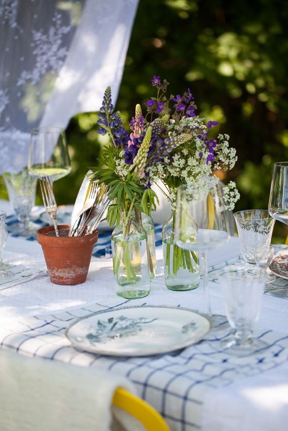 clear bottles with purple and white blooms are a cool summer centerpiece or decoration