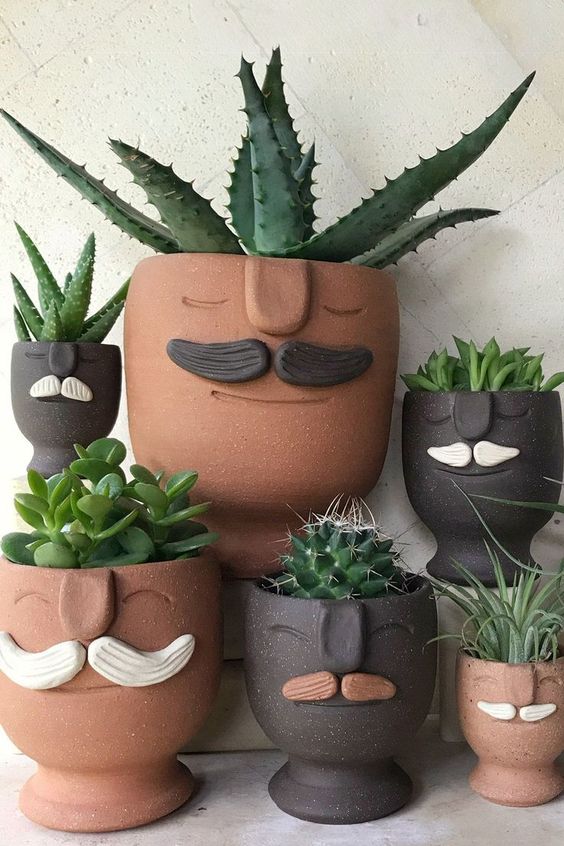 quirky terracotta and black planters with moustaches and succulents are a fun and bold idea to rock