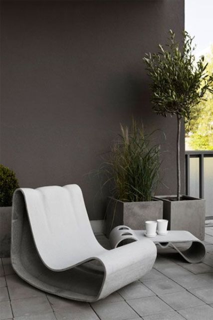 a Scandinavian outdoor space with catchy concrete furniture and concrete planters with trees looks super edgy