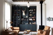 a beautiful and welcoming lviing room with a tin tile ceiling, a black built-in storage unit, a fireplace, amber leather seating furniture and a rug