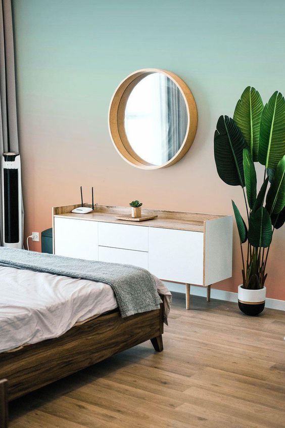 a bedroom with a gradient sunset wall, from mint to coral, a Scandinavian dresser, a dark-stained bed with neutral bedding