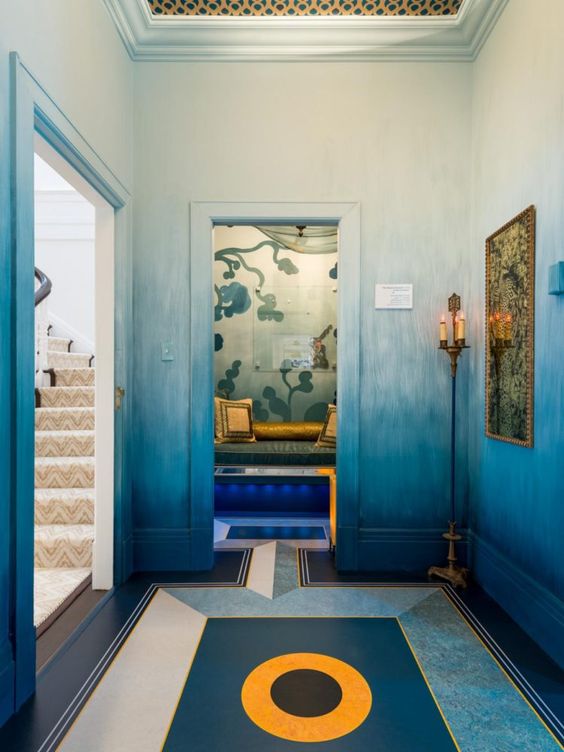 a bold and unique entryway with ombre blue walls, a bold floor with geo stencils and a small niche with a daybed
