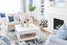 a bold summer living room with a printed rug, bold printed pillows and a striped chair plus greenery and blooms