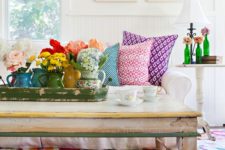 a bold summer living room with floral artworks, blooms in vases, printed pillows and a colorful floral rug for a cheerful feel