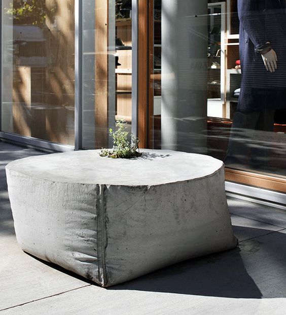 a catchily shaped outdoor concrete table with a planter in the center is a unique solution that looks fresh