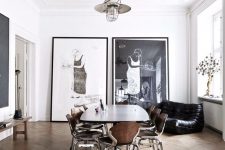 a chic Scandinavian dining space with a stucco ceiling, a dining table, modern chairs, a black loveseat and oversized artwork