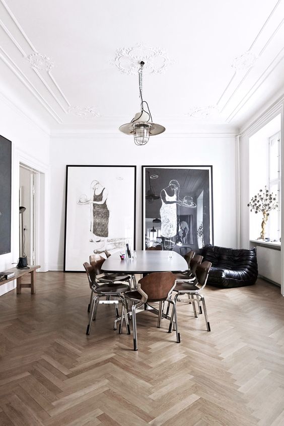 a chic Scandinavian dining space with a stucco ceiling, a dining table, modern chairs, a black loveseat and oversized artwork