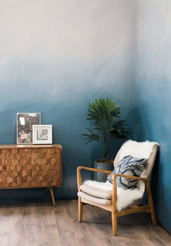 a chic corner with blue ombre walls, a catchy fishscale credenza, a neutral chair, a potted plant and some artwork