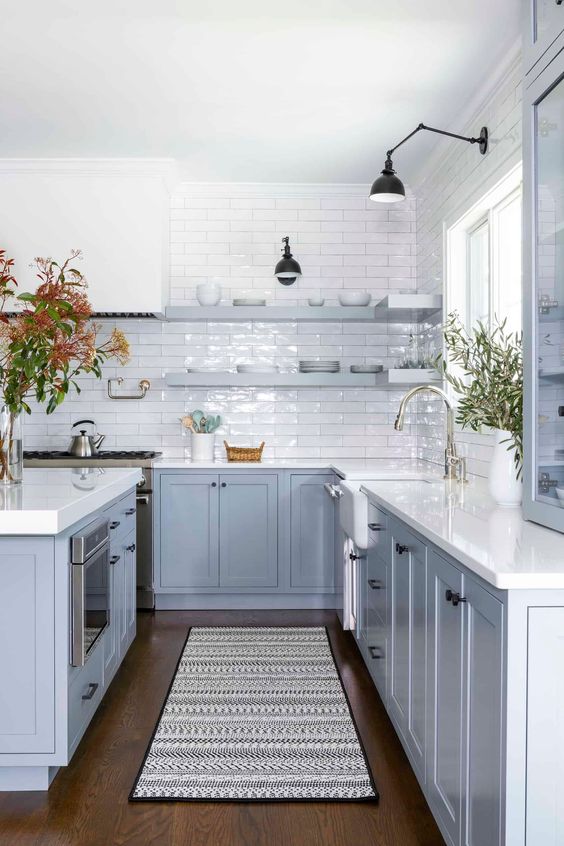 a chic ocean kitchen with shaker cabinets, white stone countertops, white tiles, open shelves and touches of black for a contrast
