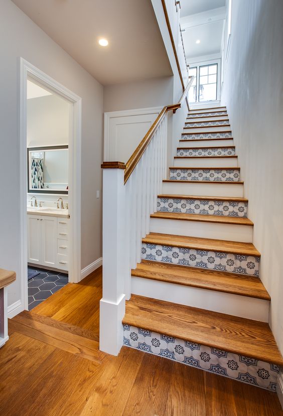 a coastal staircase with risers painted white and clad with blue patterned tiles is a beautiful idea for a seaside home