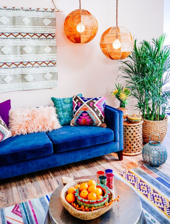 a colorful boho living room with a boho hanging, faceted lamps, a blue sofa, colorful pillows and a rug