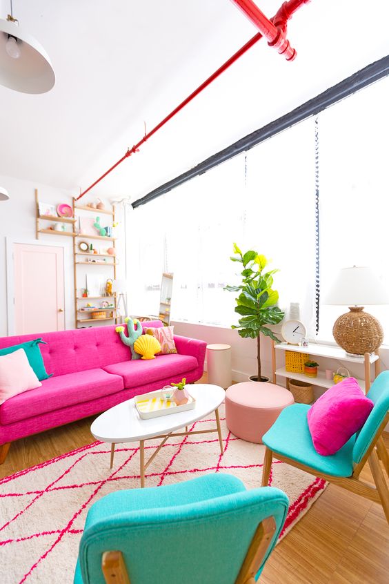 a colorful living room with a pink sofa, turquoise chairs, bright pillows of catchy shapes for fun