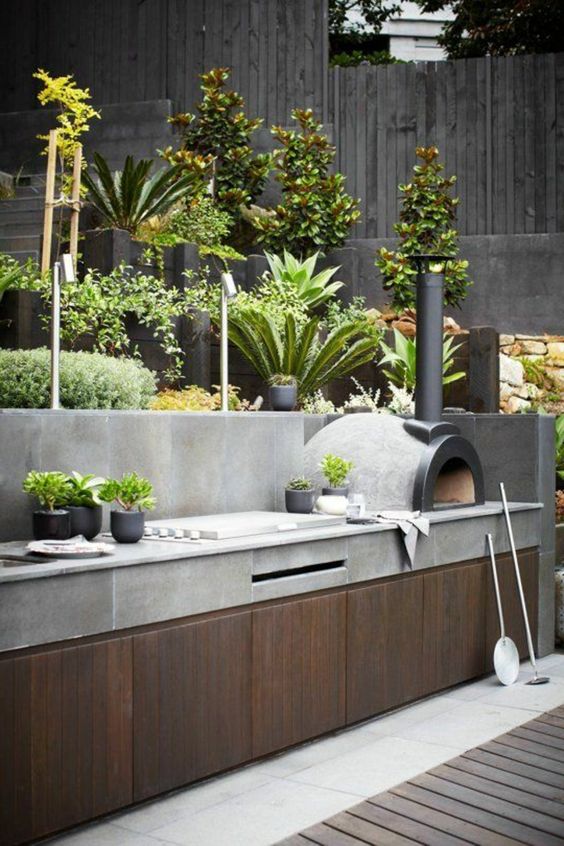 a concrete and wood kitchen with a stove and potted herbs is a great place to cook food - everything from pizzas to salads