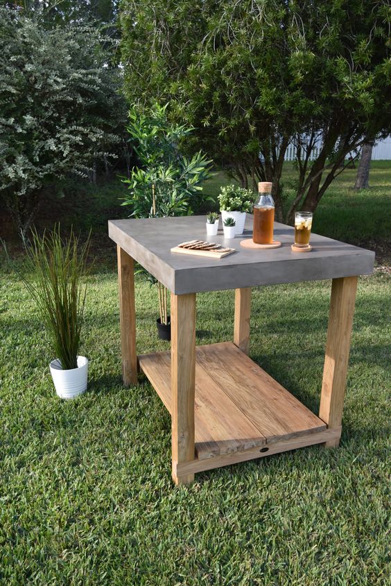 a concrete and wood outdoor table with potted greenery can be used for many things including serving drinks