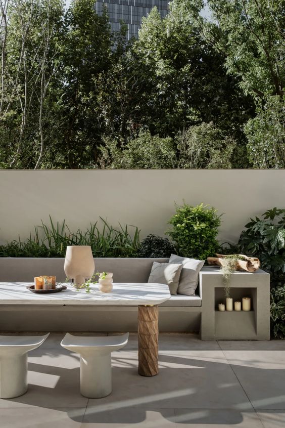 a contemporary terrace with a concrete sofa and a side table, neutral upholstery, a wood and stone table and matching chairs