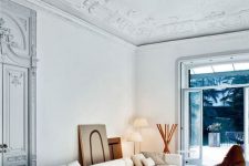 a fantastic neutral lving room with a gorgeous stucco ceiling and doors, a modern white sofa, a low coffee table and a leather chair