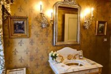 a gorgeous and refined powder room with a gold ceiling and gold furniture legs and faucets