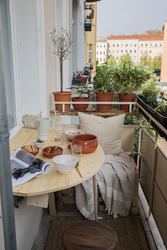 a light-stained wooden folding table is a lovely idea for a tiny balcony, you may use it as a planter stand or to serve something