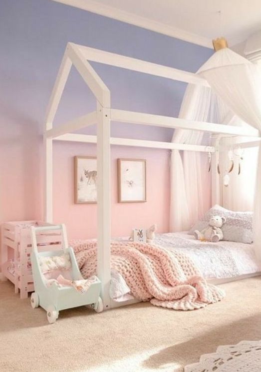 a lovely kid's room with a gradient blue to pink accent wall, a house-shaped bed and some lovely pastel toys