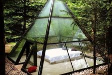a metal and glass pyramid with a bed inside to enjoy the views around and merge with nature