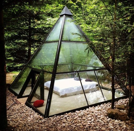 a metal and glass pyramid with a bed inside to enjoy the views around and merge with nature