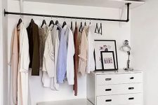 a modern bedroom with a makeshift closet, with a couple of dressers, a holder with clothes hangers and an open shelf, that’s enough for those who don’t have a lot of clothes