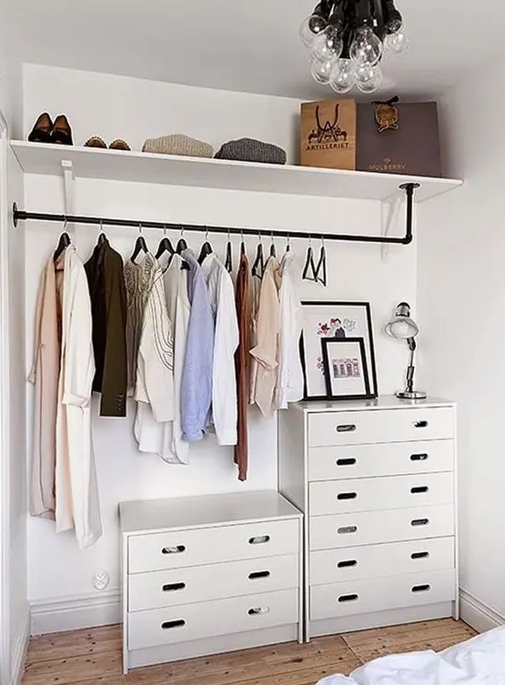 a modern bedroom with a makeshift closet, with a couple of dressers, a holder with clothes hangers and an open shelf, that's enough for those who don't have a lot of clothes