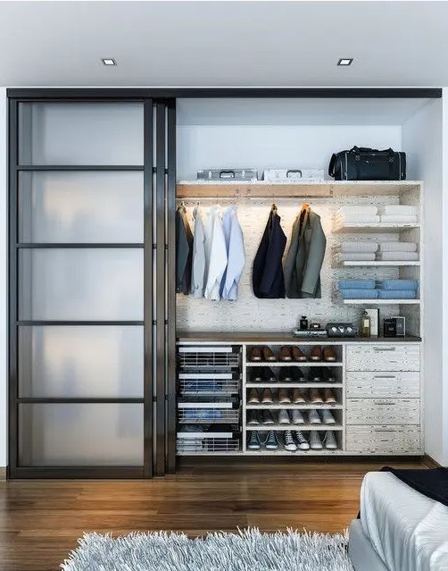 a modern bedroom with sliding glass doors that hide an organized closet with additional shelves and lights