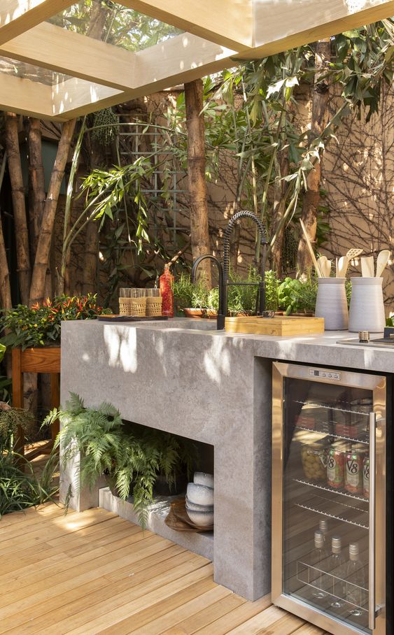 a modern kitchen of concrete with a built-in sink, a fridge and roof over the space is a great nook to cook something delicious