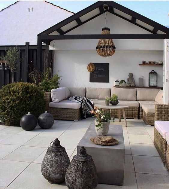 a modern neutral terrace with touches of boho, with a neutral sectional, a concrete table, a bead chandelier and some lovely vases