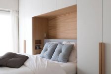 a neutral bedroom with a large sleek storage unit, a niche with built-in shelves and a bed with cozy and soft bedding is amazing