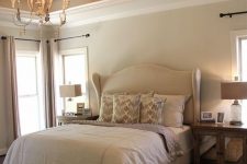 a neutral vintage bedroom with tan walls, a coffered ceiling with a vintage chandelier, neutral and stained furniture
