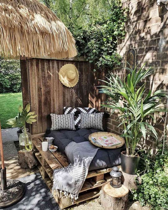 a simple boho bedroom nook with a pallet bed with pillows, potted greenery around located so that the sun didn't get it