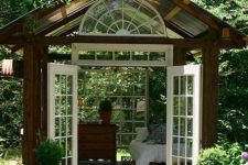 a small wood and glass garden house with comfortable vintage furniture and garden views is a lovely outdoor bedroom