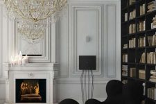 a sophisticated Parisian living room with a stucco ceiling, paneled walls, a built-in bookcase, a fireplace, a black chair and a pouf and an oversized chandelier