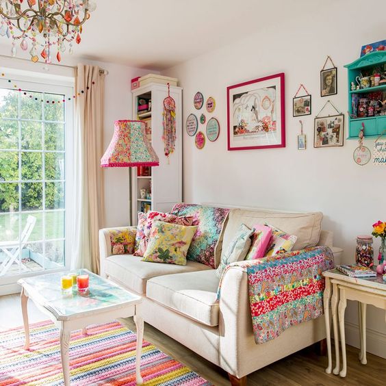 a summer living room with a bold gallery wall, printed pillows and a blanket, a bright lamp and chandelier