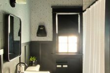 a vintage black and white bathroom with a tin tile ceiling, paneled walls, vintage appliances and black fixtures