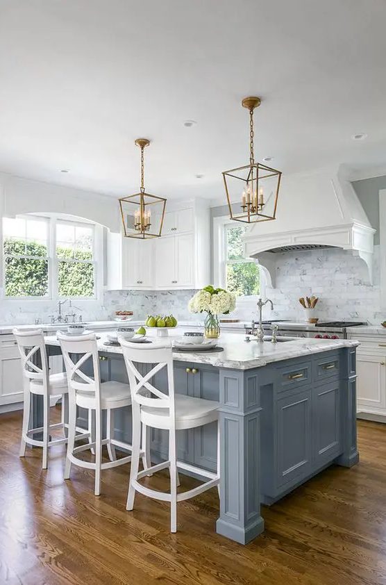 a vintage coastal kitchen is given a coastal touch with a pale blue kitchen island, a chic look with brass touches and a vintage feel with white stools