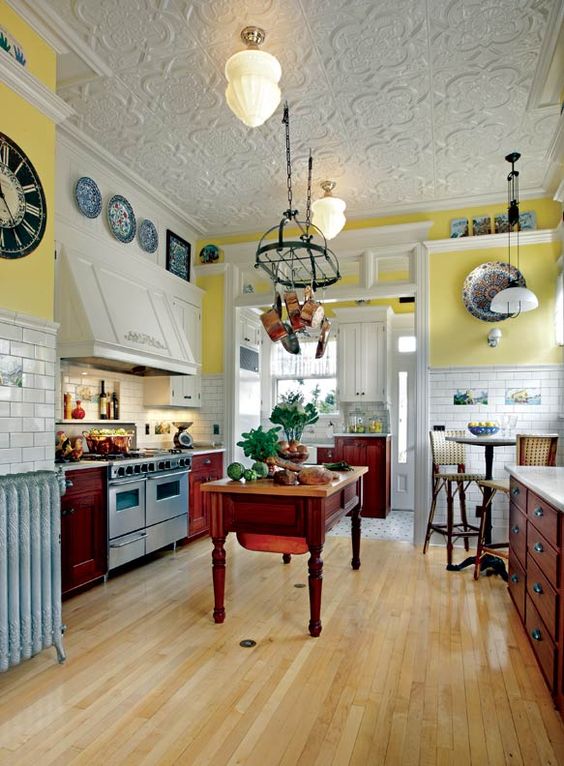 a vintage kitchen with bold yellow walls, white subway tiles, dark stained cabinets, a kitchen island and a pan holder