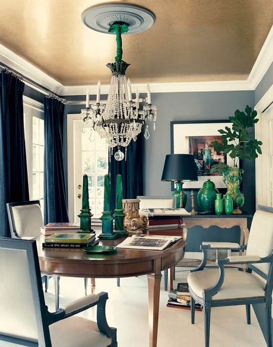 an elegant dining room with refined furniture, a sophisticated chandelier and a gold ceiling
