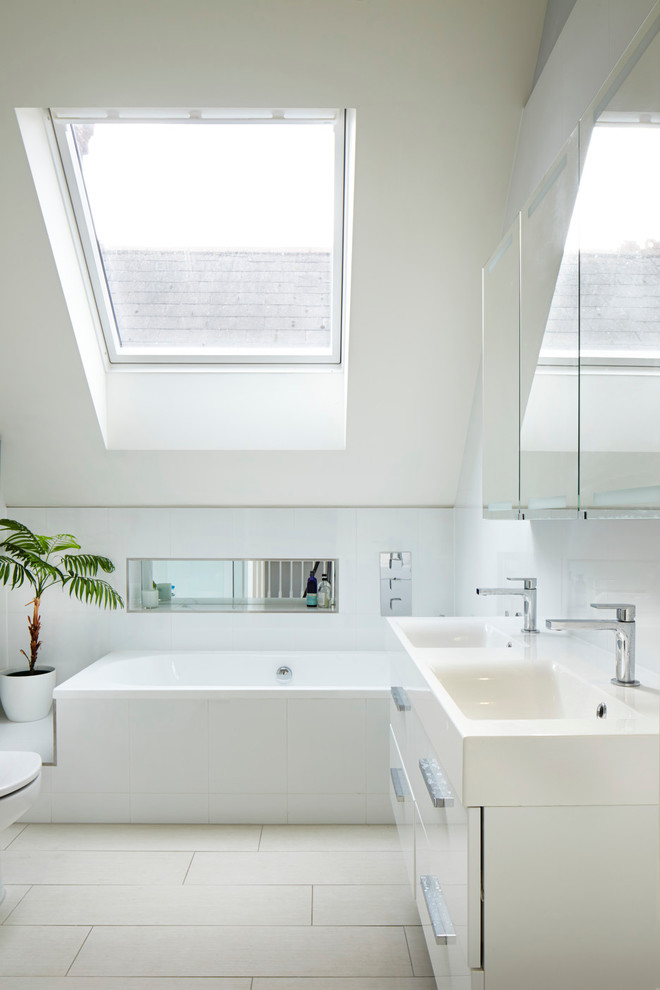 a large attic bathroom in neutrals and light blue with a large skylight and a double vanity  (Dyer Grimes Architecture)
