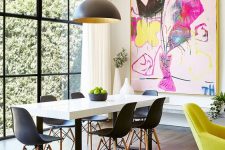 a Scandinavian dining room with a white and black dining table, black Eames chairs, a black pendant lamp and a super colorful graffiti artwork