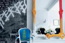a black and white graffiti, a mirror in a bold frame from white and yellow to hot red, a blue chair with a bit of graffiti