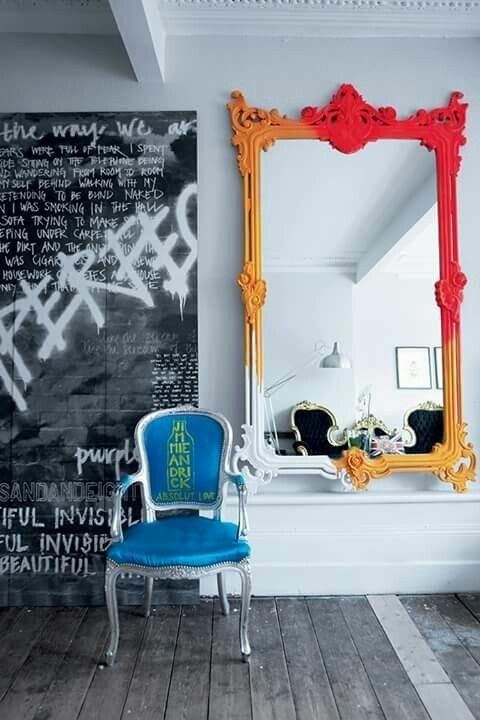a black and white graffiti, a mirror in a bold frame from white and yellow to hot red, a blue chair with a bit of graffiti