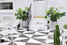 a black and white patio with a tiled floor, white dining furniture and a black umbrella, potted greenery and cacti
