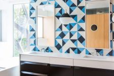 a bold bathroom with a striped black and white tile floor, a black vanity, white appliances, a blue, black and white tile wall